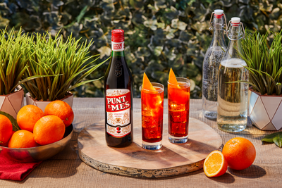 Punt e Mes Spritz mit zwei Gläsern Spritz auf einem Tisch mit Orangen