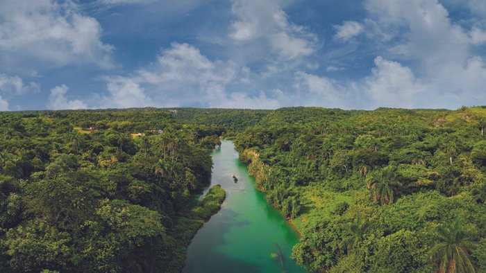 Bild des kubanischen Urwaldes, aus dem der Rum Kawama stammt. In der Mitte des Bildes verläuft ein malerischer Fluss durch die üppige, grüne Landschaft