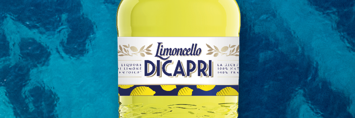 Die gelbe Limoncello DiCapri Flasche vor der wunderschönen blauen Küste von Capri. Das Original der Insel Capri