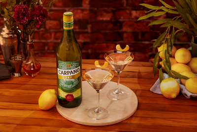 Carpano Dry und Martini Glas auf einem Tisch mit Zitronen