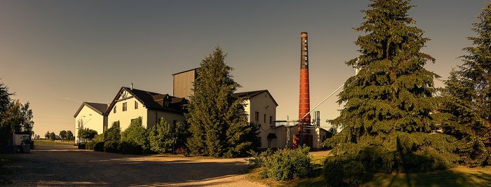 Zu erkennen ist die Chopin Vodka Distillery umgeben von Bäumen.