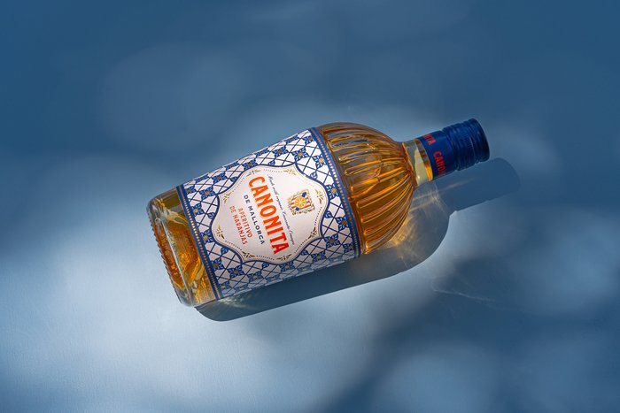 Die Canonita de Mallorca Aperitif Flasche liegt auf einem blauen Hintergrund 