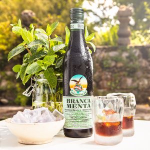Brancamenta Flasche auf einem Tisch mit zwei gefüllten Gläsern, Eis und Minze